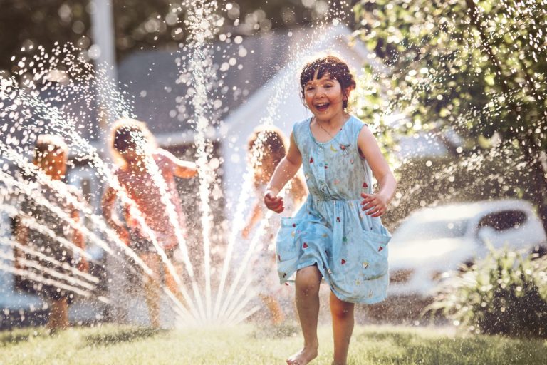 weekly watering recommendations, kids running through lawn sprinkler
